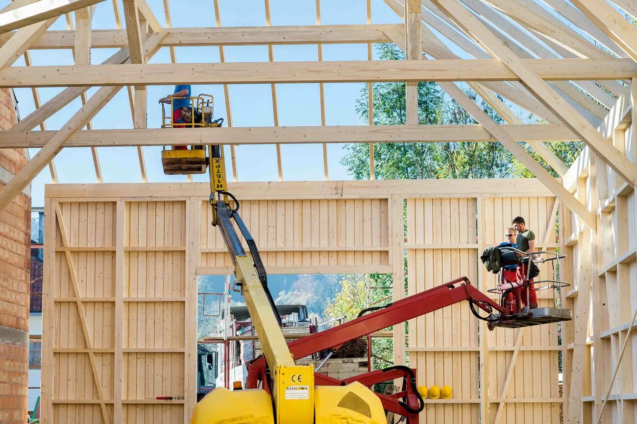 Halle in Holzrahmenbauweise im Rohbau, ein Arbeiter auf einer gelben Hebebühne